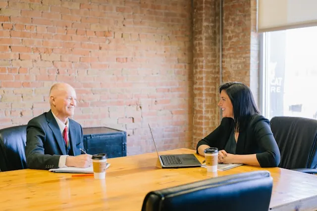 A woman and a man speaking in a board meeting